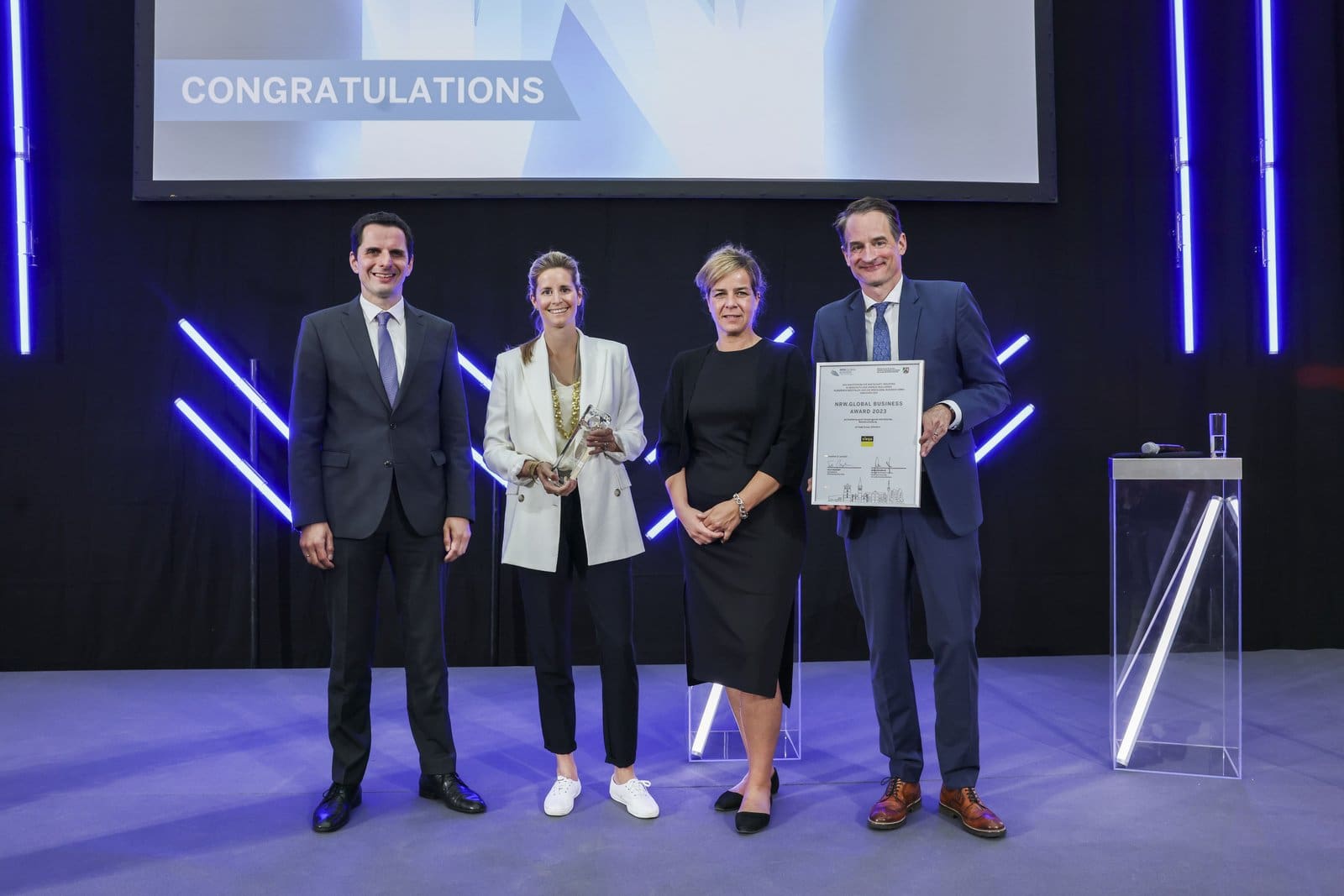 Anna Viegener (2.v.l.), Vorsitzende des Geschäftsausschusses der Viega Holding GmbH & Co. KG, nimmt den NRW.Global Business Award aus den Händen von Mona Neubaur, Ministerin für Wirtschaft, Industrie, Klimaschutz und Energie und Felix Neugart, Geschäftsführer von NRW.Global Business entgegen. Die Laudatio für Viega hielt Christian Pospischil (l.), Bürgermeister der Stadt Attendorn.